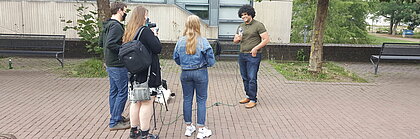 Auf dem Foto ist das Team von CampusTV zu sehen, wie es einen Studenten befragt.