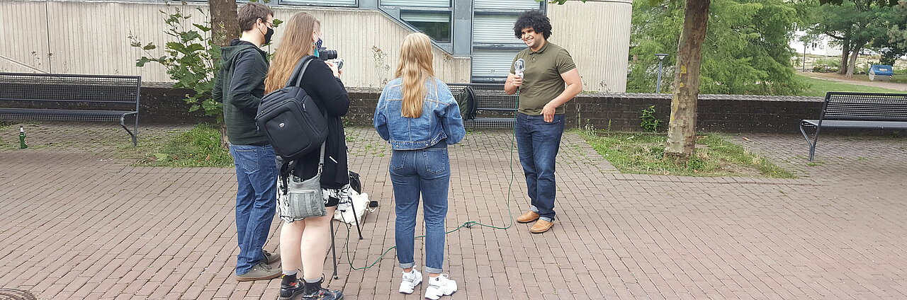 Auf dem Foto ist das Team von CampusTV zu sehen, wie es einen Studenten befragt.