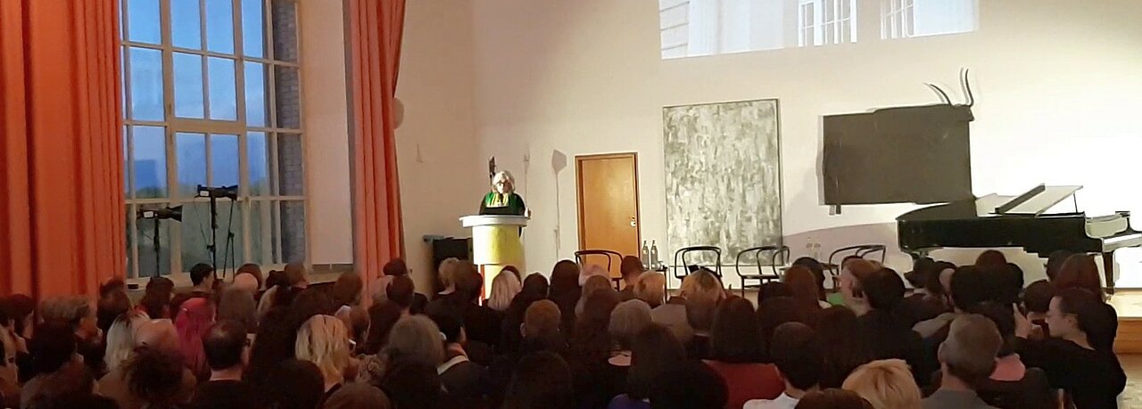 In der Aula der Kunstakademie Düsseldorf hält die Rektorin eine Rede vor Publikum