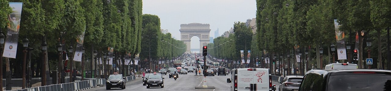 Man sieht den Arc de Triomphe in Paris am Ende der Champs Élyséese