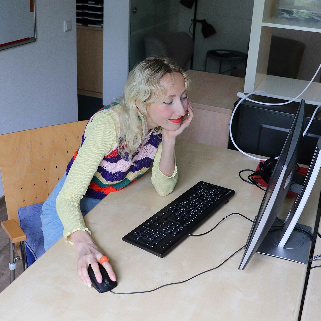 Zu sehen ist eine Frau, die an einem Computer sitzt