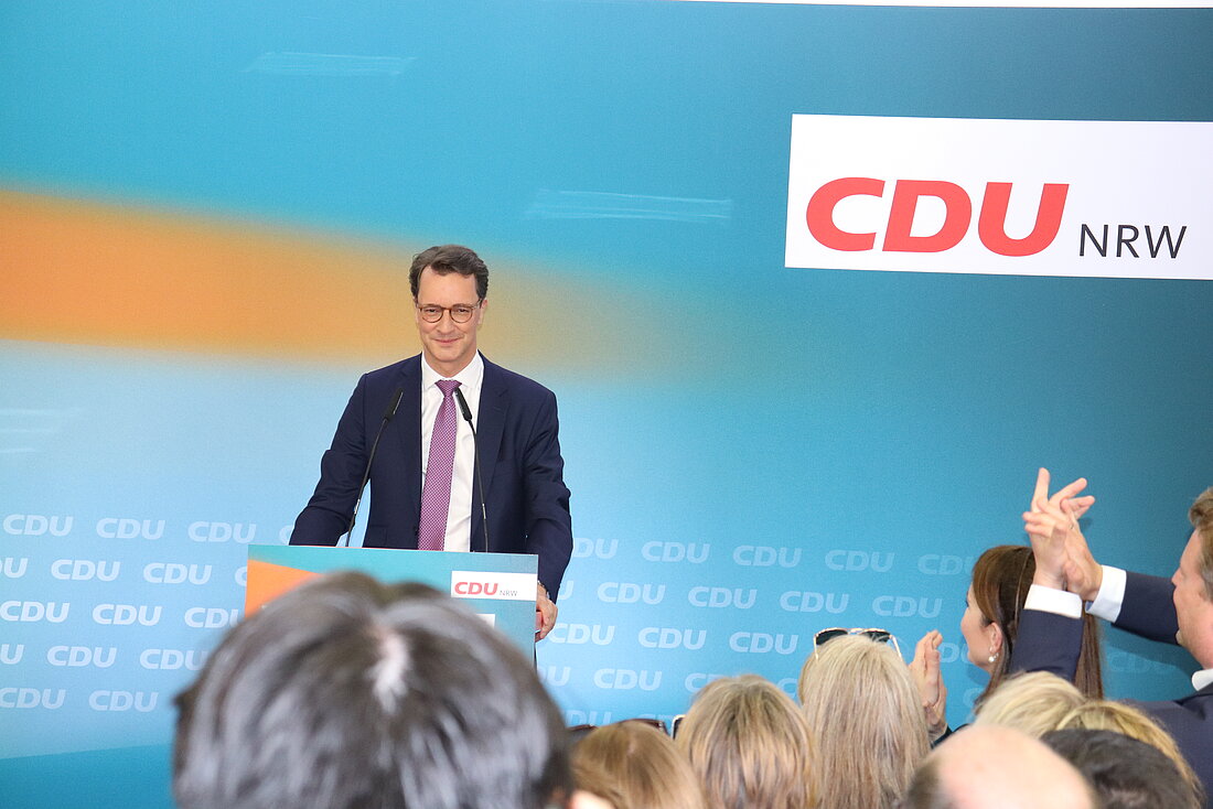 Spitzenkandidat der CDU, Hendrik Wüst, steht vor einem CDU Logo und hält eine Rede.
