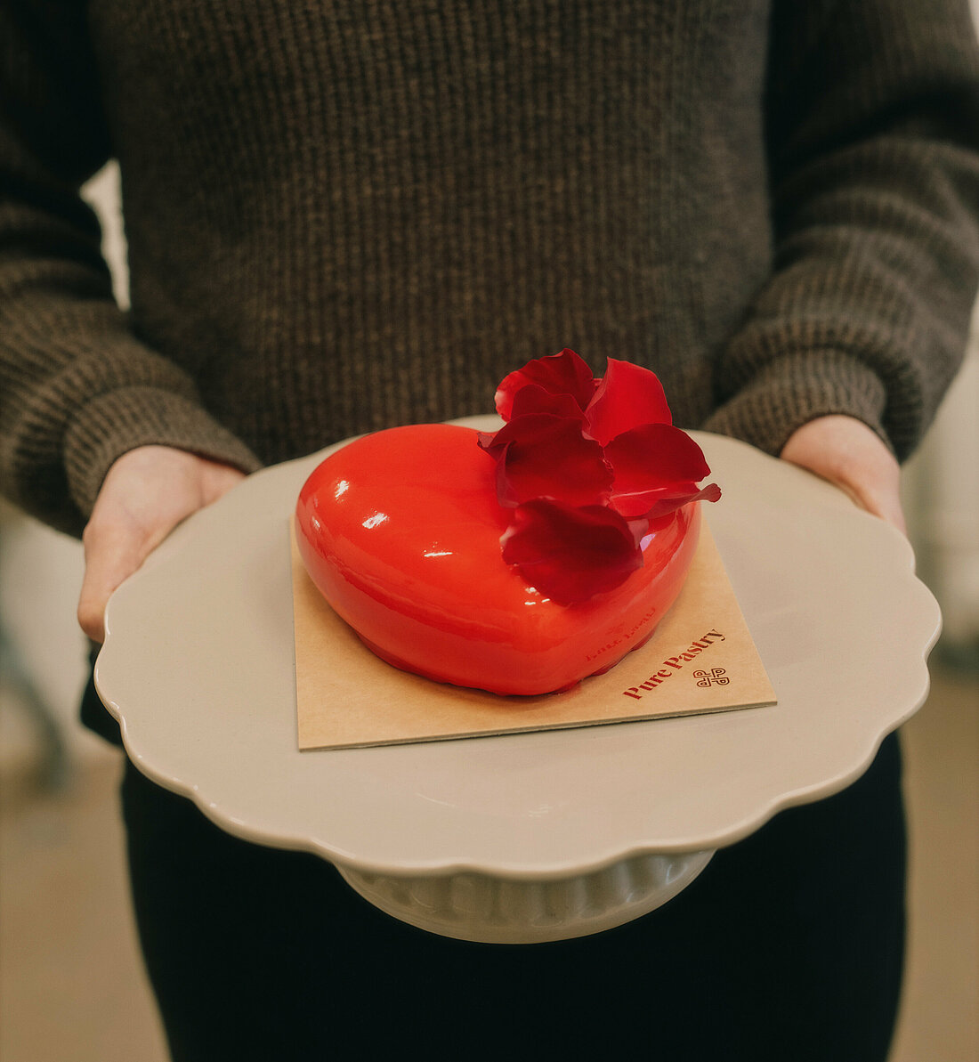 Frau hält ein Tablet mit herzförmigem Dessert