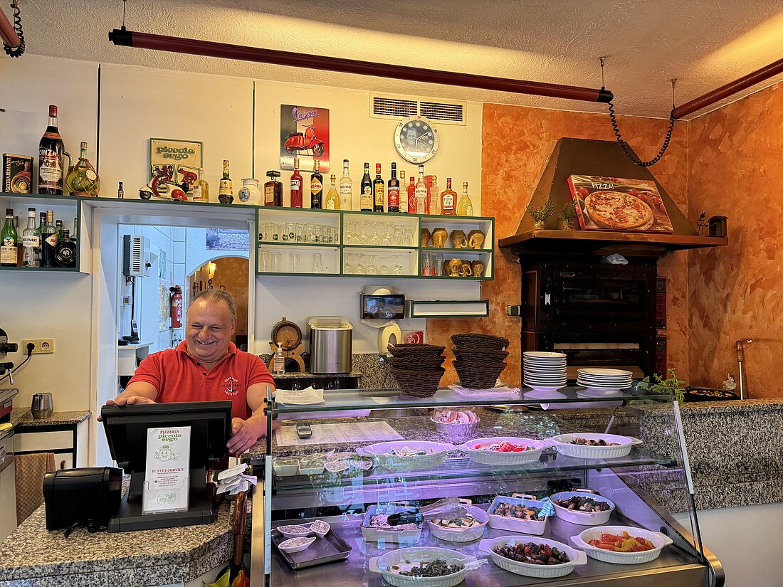 Auf dem bild sieht man die Theke des Restaurants mit ihrem lächelnden Inhaber.