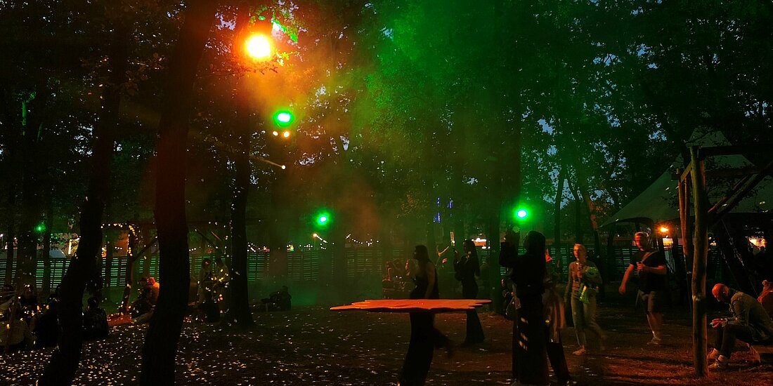 Auf dem Foto ist der Stadtgarten bei Nach zu sehen. Rotes und Grünes Licht spiegeln sich im Bild. Einige Besucher:innen machen Fotos mit ihren Handys um das einzufangen.
