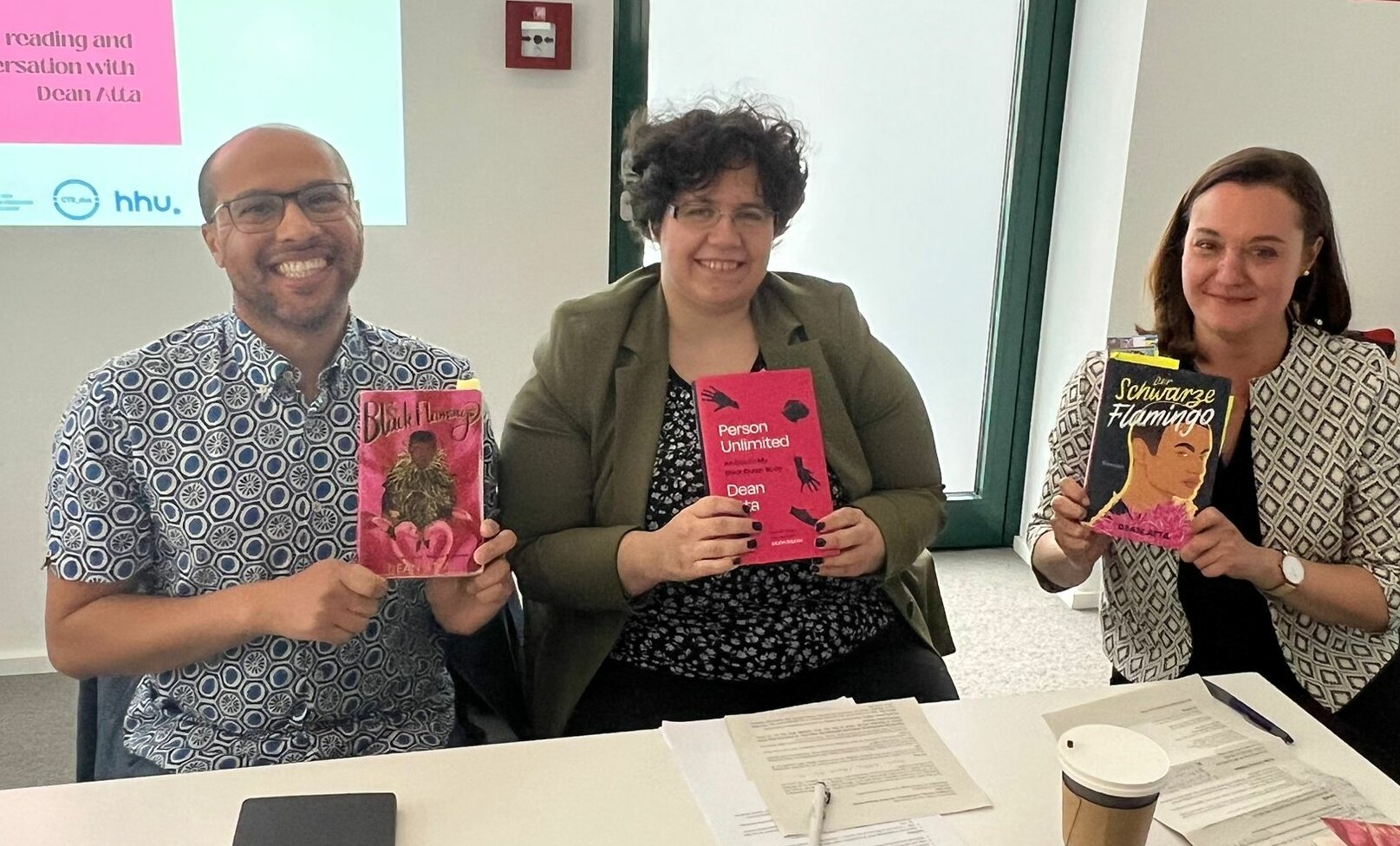 Auf dem Foto sind von links nach rechts, Autor Dean Atta, Dr. Bettina Burger und Dr. Hannah Pardey mit der englischen Ausgabe von Der Schwarze Flamingo zu sehen.
