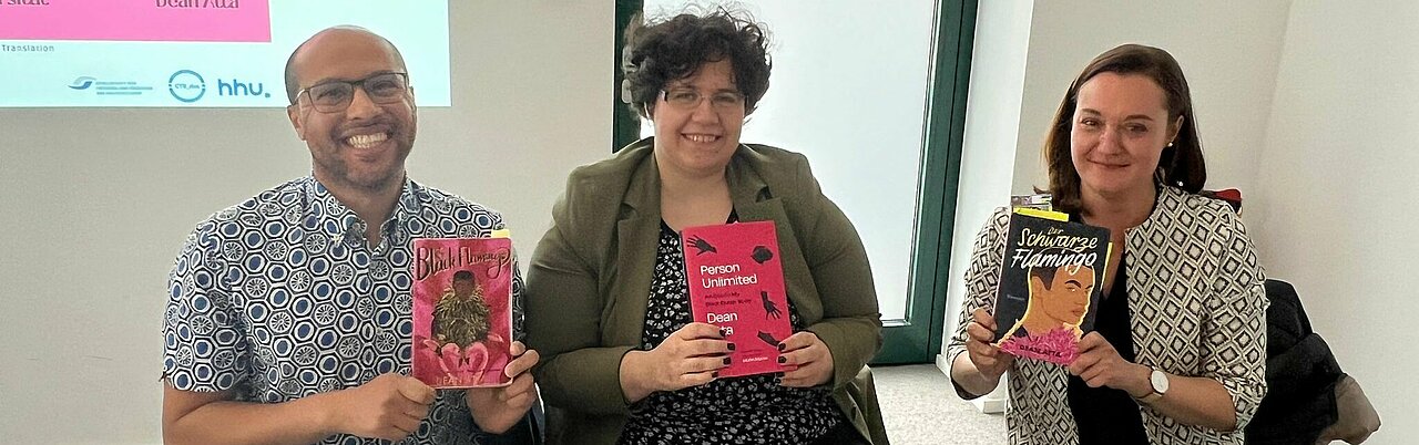 Auf dem Foto sind von links nach rechts, Autor Dean Atta, Dr. Bettina Burger und Dr. Hannah Pardey mit der englischen Ausgabe von Der Schwarze Flamingo zu sehen.