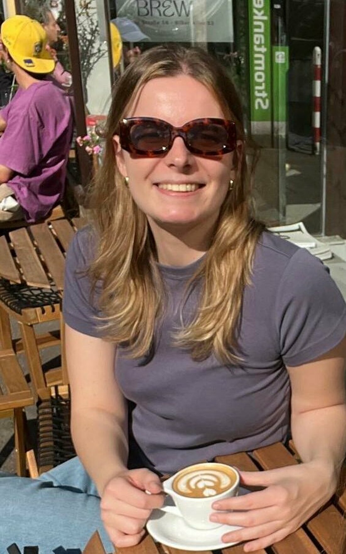 Valeska Ridzewski lächelt vor einem Kaffee sitzend in die Kamera.