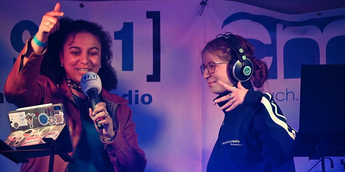 Auf dem Foto sind hrd-Redakteurin Jasmin mit Moderatorin Asya auf einer kleinen Bühne.