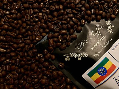 Auf dem Bild sieht man eine Kaffeeverpackung aus der Die-Kaffee-Rösterei mit gerösteten Kaffeebohnen.