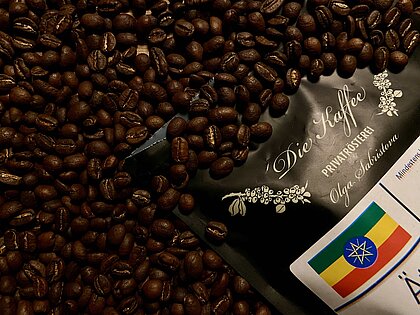Eine Packung - Viele Bohnen (Foto: Lea Wiesten) Auf dem Bild sieht man eine Kaffeeverpackung aus der Die-Kaffee-Rösterei mit gerösteten Kaffeebohnen.