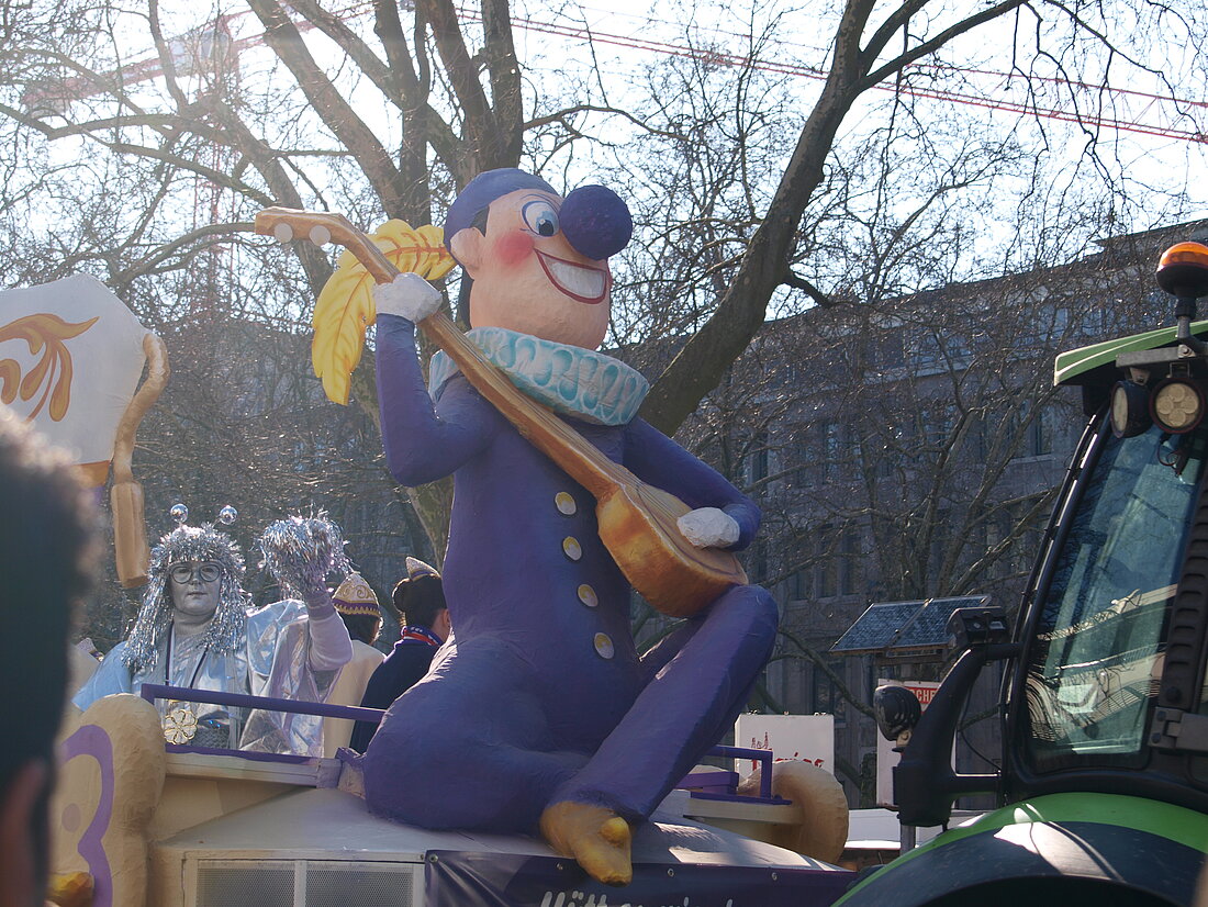 Ein Till Eulenspiegel Mottowagen an deren Spitze ein riesen großer Till sitzt und Laute spielt