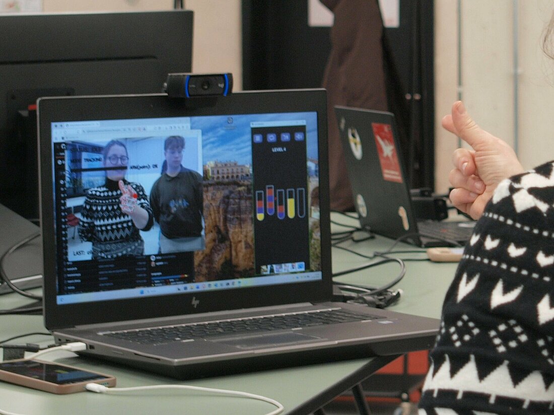 Eine Frau spielt kontaktlos ein Handyspiel an einem Laptop