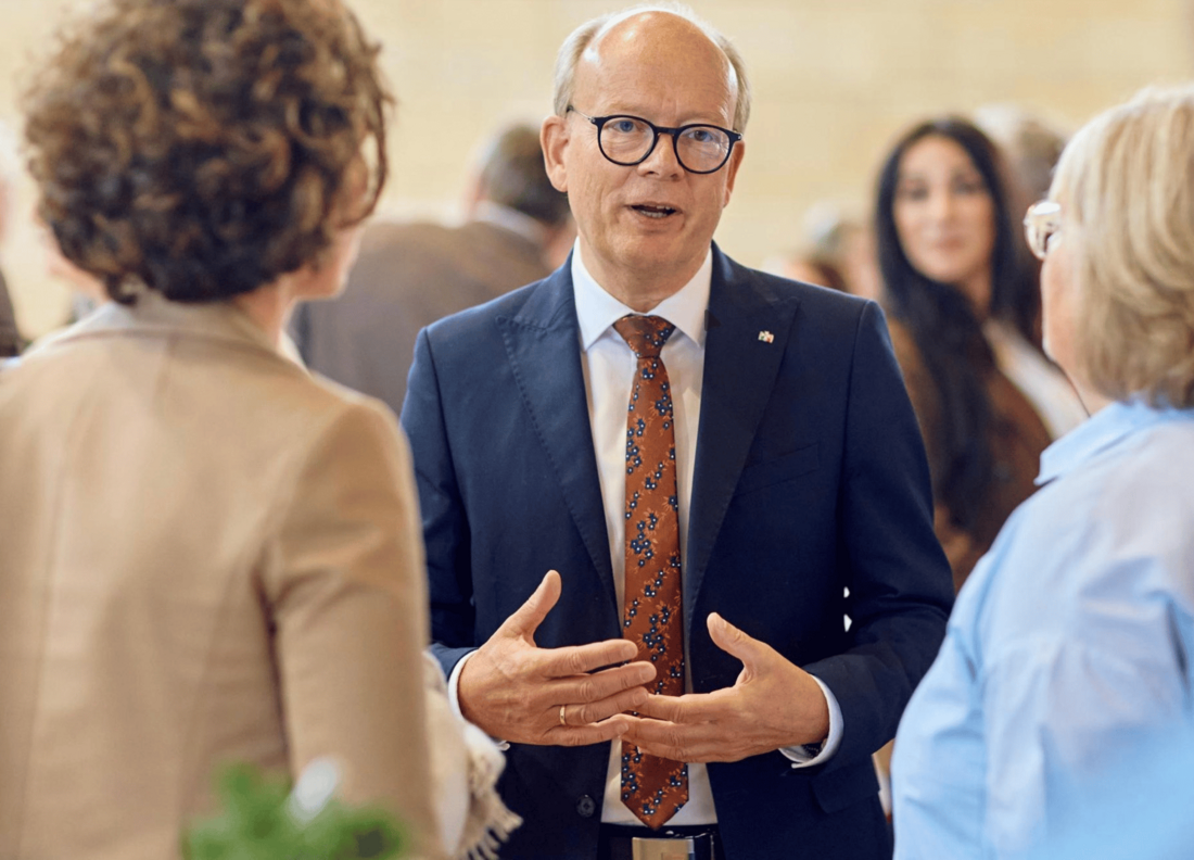 Der Präsident des Landtags, André Kuper, begrüßte die Teilnehmenden des Bürgerrats. Man sieht zwei Teilnehmerinnen von hinten.