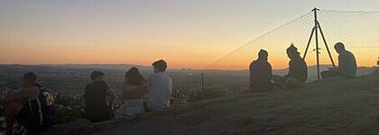 Sonnenuntergang in Granada, Spanien: Auch hier können Studierende der HHU ein Auslandssemester machen. (Foto: Noa Leimkühler) Mehrere Menschen sitzen bei Sonnenuntergang auf einem Hügel.