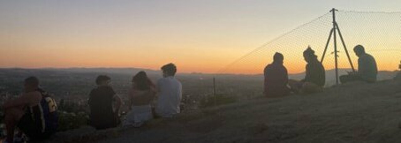 Sonnenuntergang in Granada, Spanien: Auch hier können Studierende der HHU ein Auslandssemester machen. (Foto: Noa Leimkühler) Mehrere Menschen sitzen bei Sonnenuntergang auf einem Hügel.
