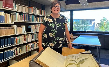 Auf dem Foto sind die Hände der Historikerin Dr. Teresa Schröder-Stapper zu sehen, die eine Tabak Pflanze in einem Buch zeigt (Foto: Valeska Ridzewski)