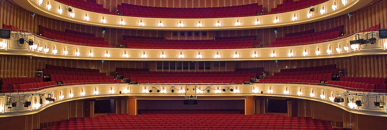 Zu sehen ist der Aufführungssaal des Düsseldorfer Opernhauses mit frontalem Blick von der Bühne auf die leeren Zuschauerplätze. 