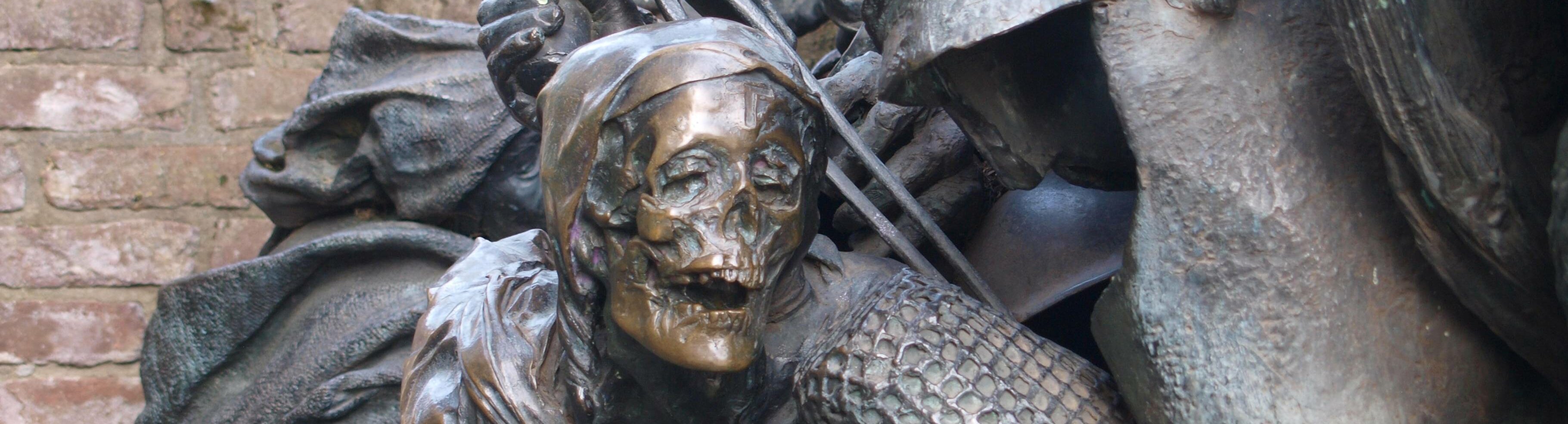 Eine bronze Statue von einem Ritter, der nur noch ein Skelett in Rüstung darstellt.