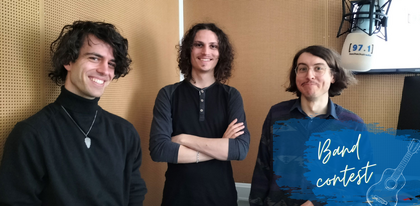 Auf dem Foto sind drei Mitglieder der Band Discoville zu sehen. Sie stehen nebeneinander und lächeln in die Kamera. Ganz rechts ist ein weißes Mikrofon mit dem Logo von hochschulradio düsseldorf im Bild.