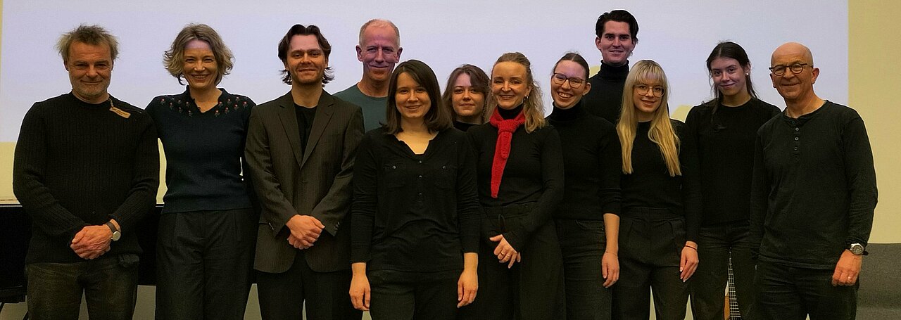 Auf dem Foto ist das Team von der Hörbuch Performance zu sehen. Sie stehen in einer Reihe und lächeln in die Kamera. 