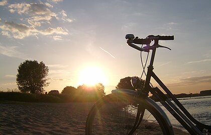 Ein Fahrrad am Strand beim Sonnenuntergang.