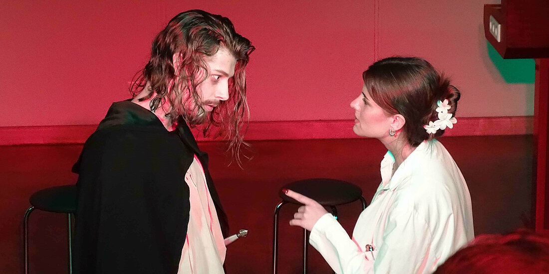 Auf dem Bild sind Ratti und die Doktorin zu sehen. Sie stehe sich gegenüber und schauen sich intensiv an. Die Doktorin zeigt mit ihrem Zeigefinger auf ihn. 