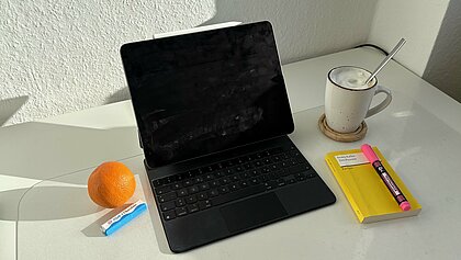 Man sieht eine ruhige Lernumgebung mit iPad, einer Lektüre, einer Tasse Kaffee und Snacks