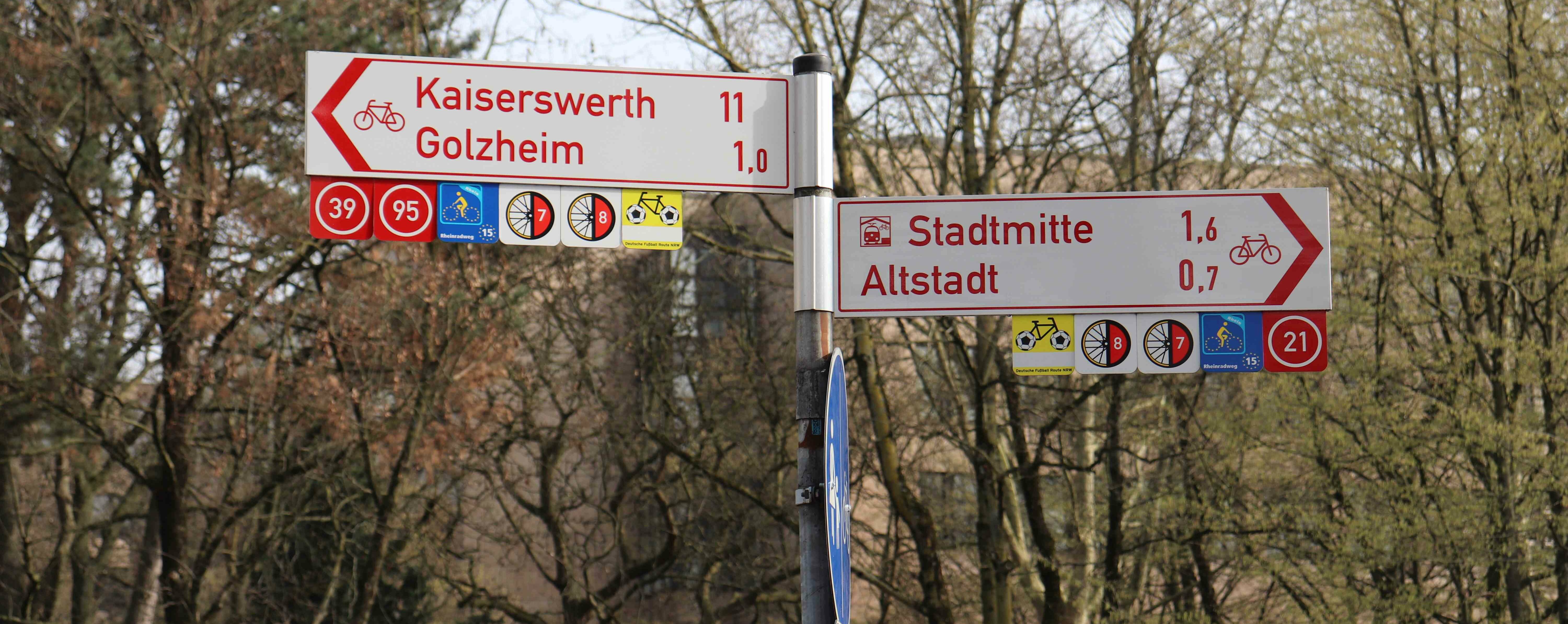Auf dem Bild sieht man Straßenschilder in Düsseldorf, die Richtung Kaiserswerth, Golzheim und Stadtmitte zeigen. 