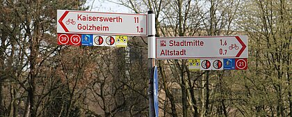 Auf dem Bild sieht man Straßenschilder in Düsseldorf, die Richtung Kaiserswerth, Golzheim und Stadtmitte zeigen. 