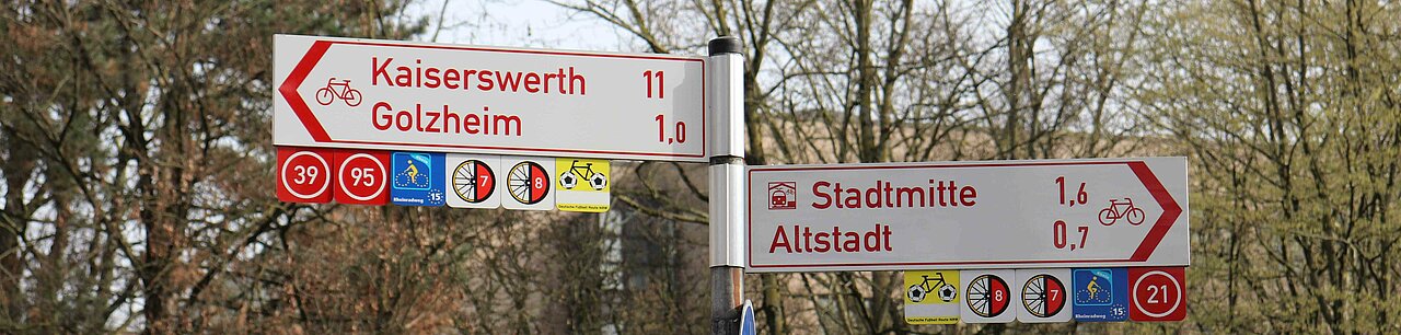 Auf dem Bild sieht man Straßenschilder in Düsseldorf, die Richtung Kaiserswerth, Golzheim und Stadtmitte zeigen. 