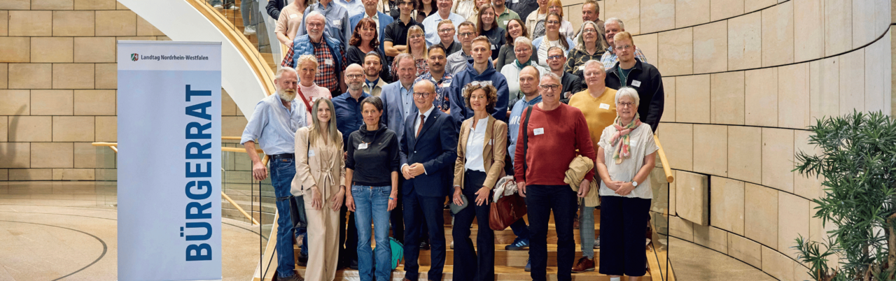 Zeigt den Bürgerrat im Landtag auf einer Treppe.