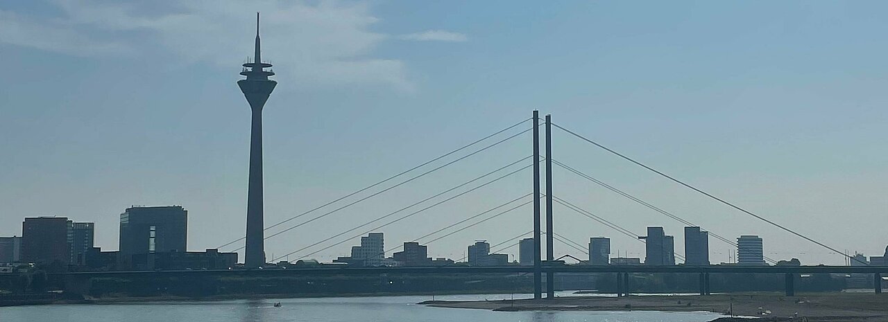 Auf dem Foto ist der Rhein und der Fernsehturm an einem sonnigen Tag zu sehen