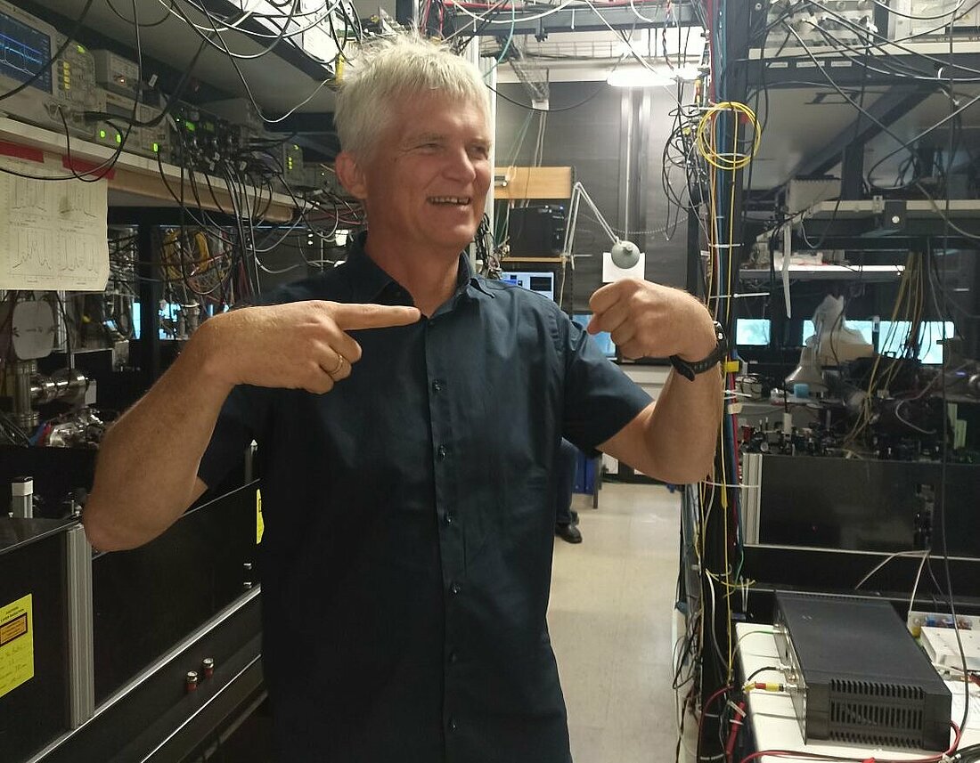 Prof. Dr. Görlitz erklärt das Fangen der Atome anhand des Vergleichs mit einem Tennisball (Foto: Anastassija Sheremet) Prof. Dr. Görlitz erklärt das Fangen der Atome anhand des Vergleichs mit einem Tennisball, eine Hand zu einer Faust geballt zeigt der Zeigefinder der anderen entgegengesetzt auf diese
