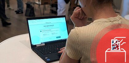 Auf dem Foto ist eine Frau zu sehen, die vor einem Laptop steht und den lokal-o-mat spielt.