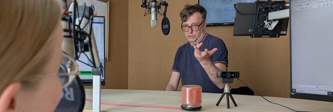 Auf dem Bild sieht man Moderatorin Hannah Vogel im Gespräch mit Christian Uffmann. Die beiden stehen in einem Radiostudio.