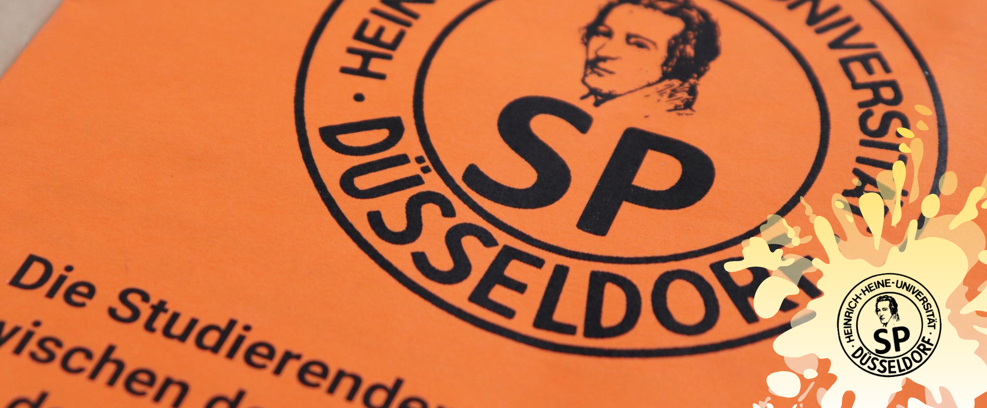 SP_Sitzung_Layout_Neumann_Tim Auf dem Bild sieht man einen orangenen Zettel mit dem Logo des Studierendenparlaments (Foto: Tim Neumann)