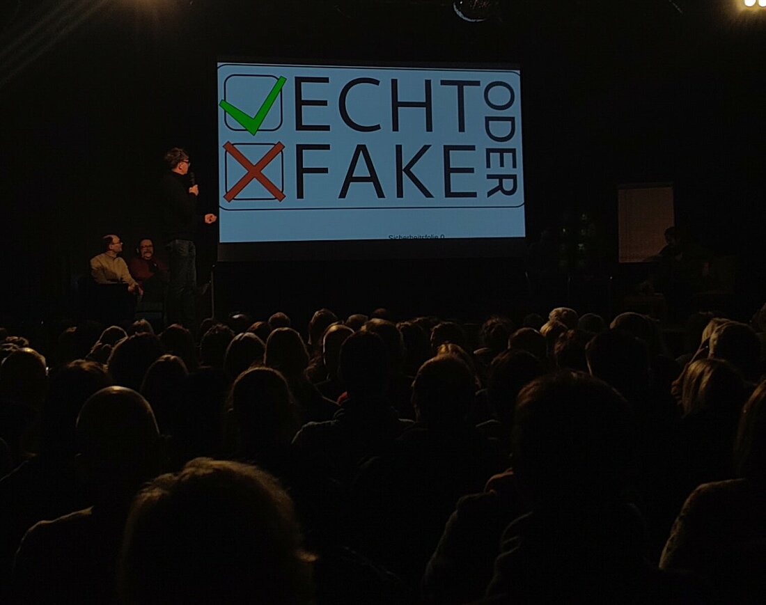Publikum schaut auf die Titelfolie mit "Echt oder Fake"