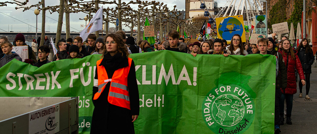 Protestzug an der Rheinpromenade, Schüler:innen halten grünes Plakat "Streik für's Klima" von "Fridays For Future Düsseldorf"
