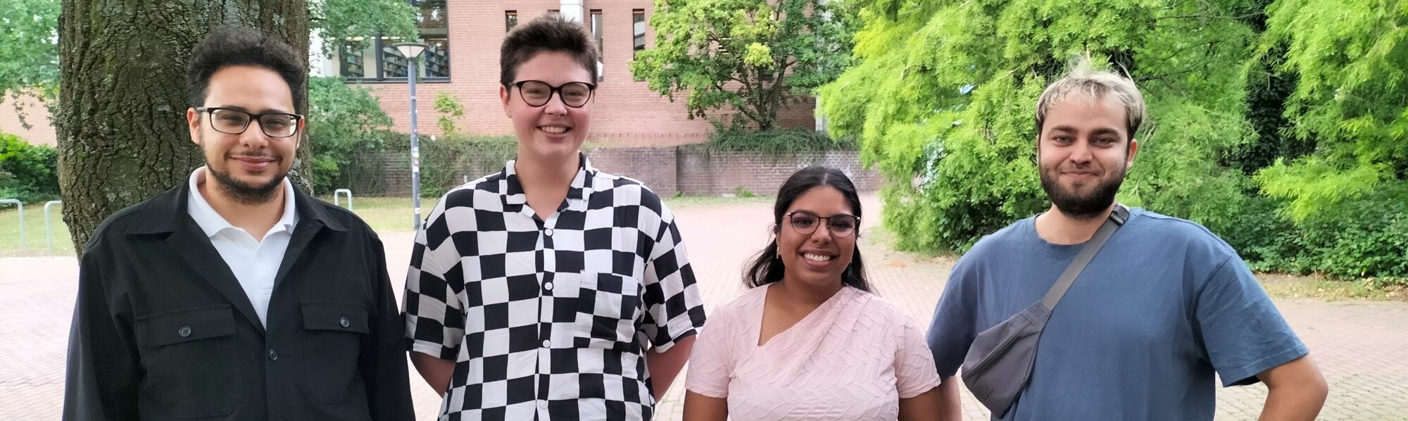 Auf dem Foto ist der bisherige AStA Vorstand zu sehen. Sie stehen in einer Reihe nebeneinander und lächeln in die Kamera.