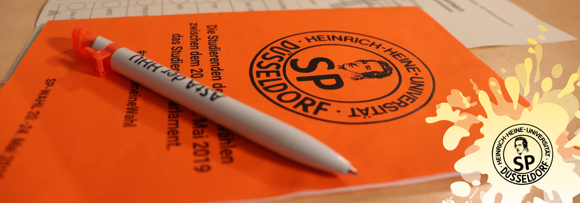 Auf dem Bild sieht man einen orangenen Zettel mit dem Logo des Studierendenparlaments (Foto: Tim Neumann)