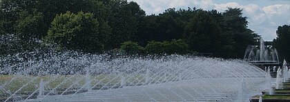 Auf dem Bild sieht man den Nordpark in Düsseldorf. Man sieht Wasserfontänen, die an beiden Seiten des Wegs sind.
