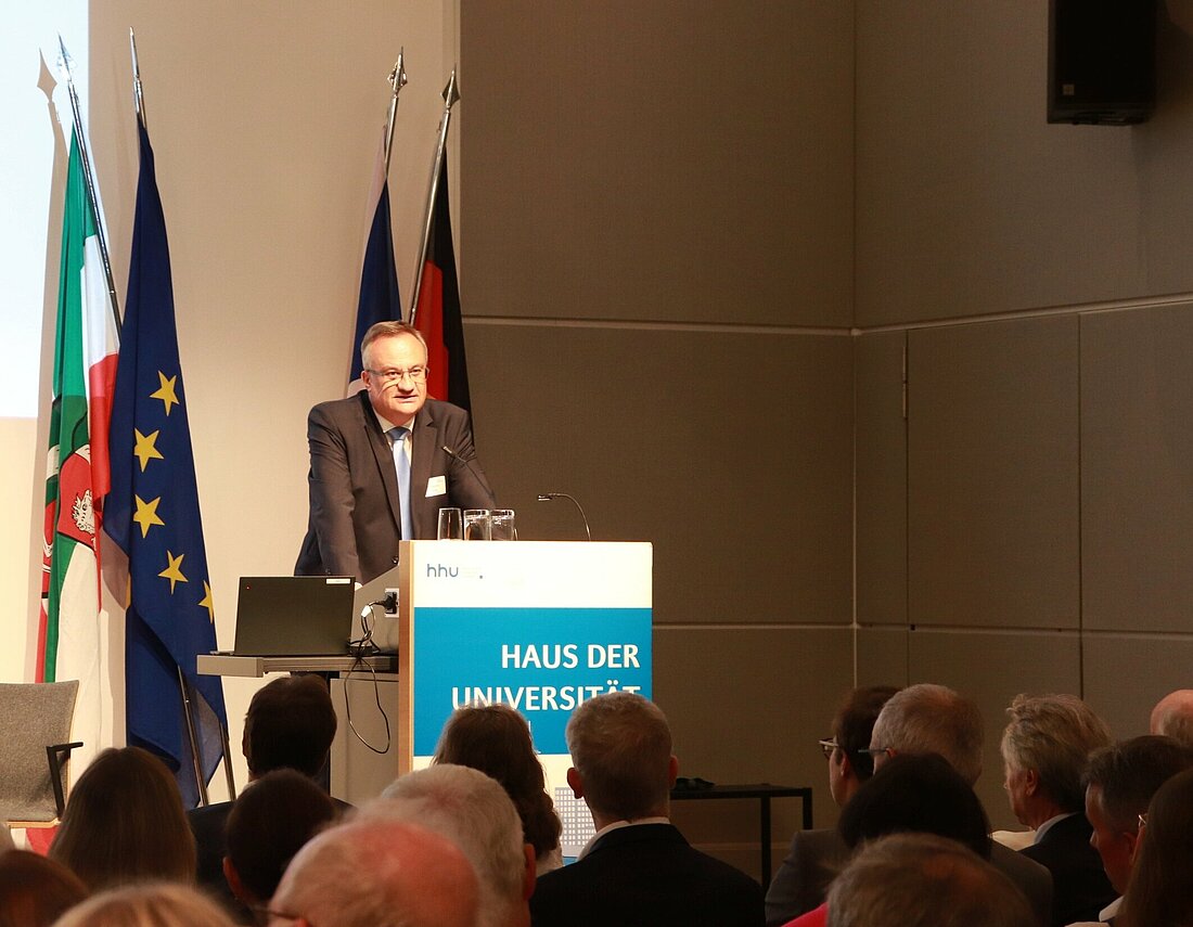 Man sieht Dr. Guido Hitze am Rednerpult, während er einen Vortrag hält. Die Gäste hören ihm zu.