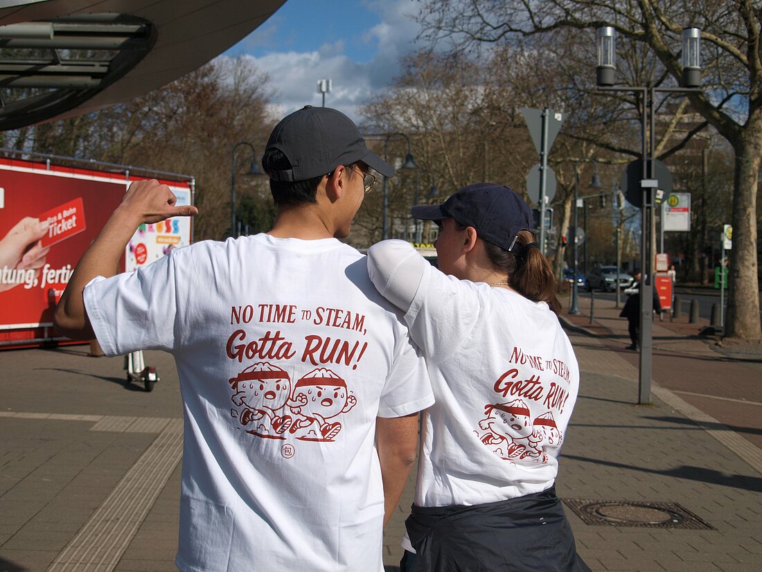 Auf dem Bild sieht man Oskar von hinten der auf sein Tshirt zeigt mit seinem Merchaufdruck