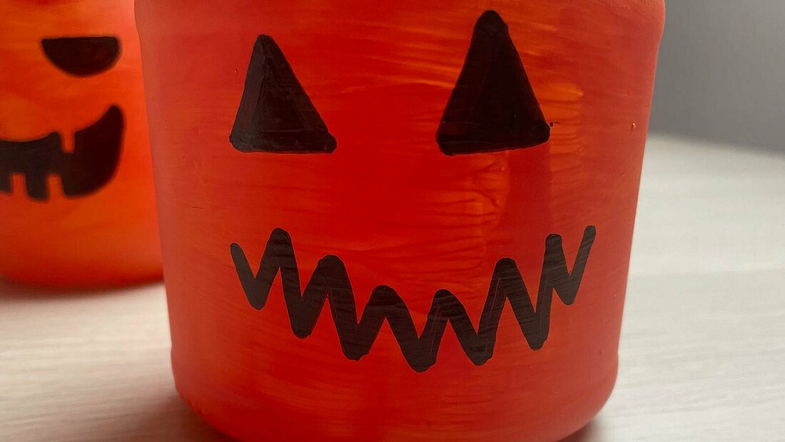 Das angemalte Gesicht hat 2 Dreiecke als Augen und einen gezackten Mund