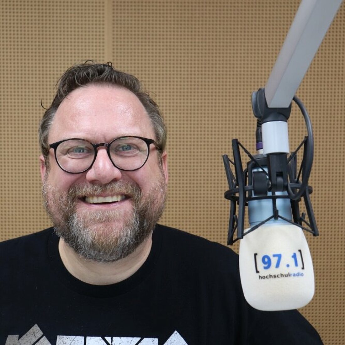 Auf dem Bild sieht man den ehemaligen Chefredakteur neben einem Mikrofon.