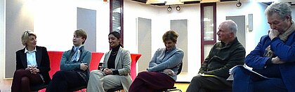 Die Teilnehmer:innen der Diskussion sitzen in einer Reihe und reden miteinander.