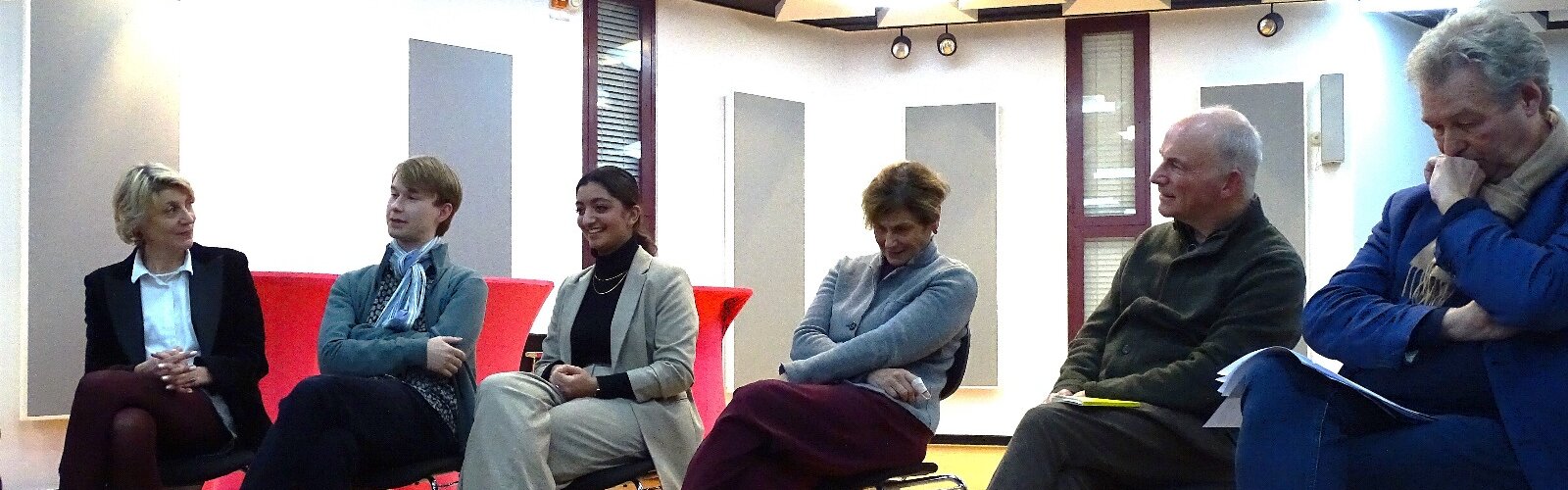 Die Teilnehmer:innen der Diskussion sitzen in einer Reihe und reden miteinander.