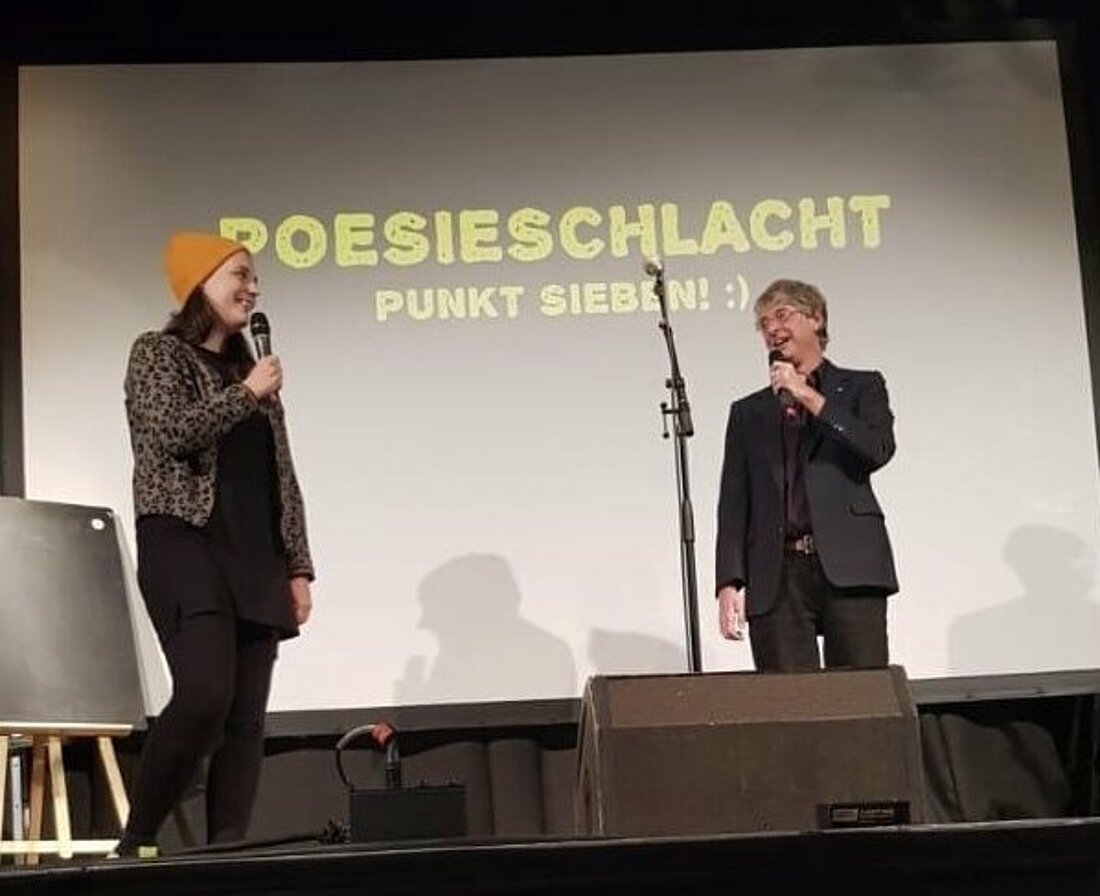 Bühne im Innenbereich des Zakk (Autor: Michaela Barbagianni) Hier sieht man die Bühne im Innenbereich des Zakk mit den beiden Moderator:innen der Poesieschlacht.