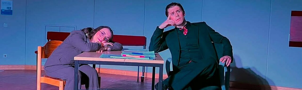 Auf dem Bild sieht man Faust und Mephisto zusammen an einem Tisch sitzen